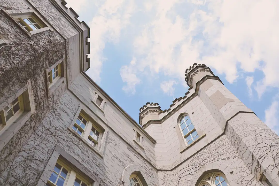 Exterior view of a light-colored, multi-story HOA-style building with arched windows, photographed from a low angle against a blue sky.