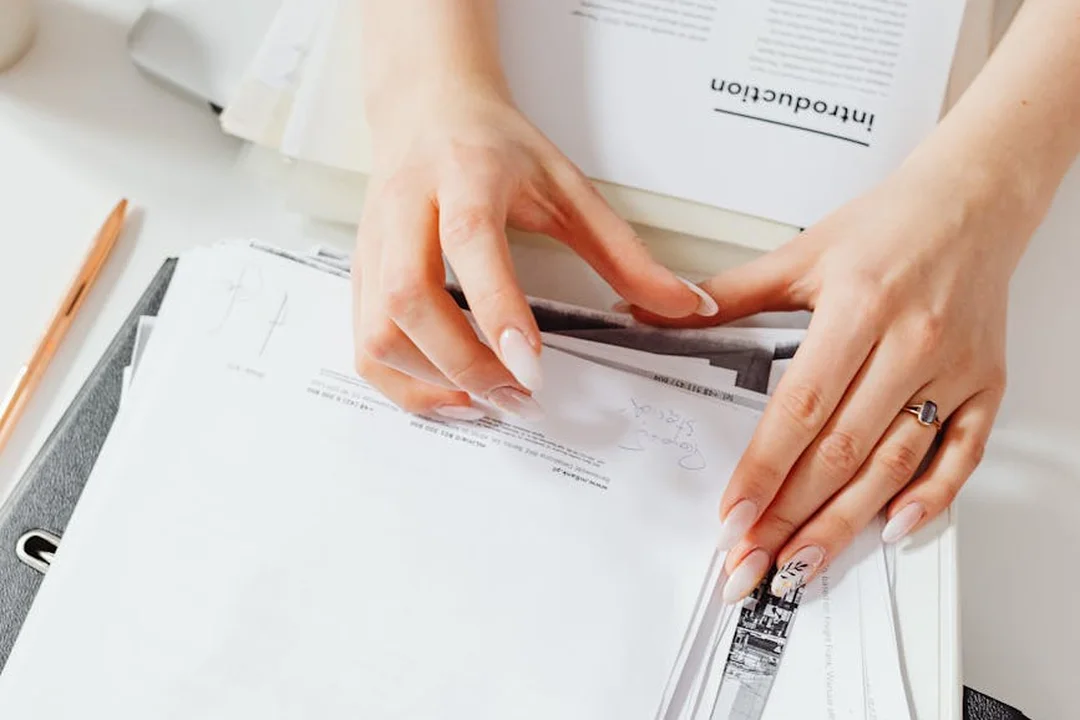 Close-up of hands arranging closing documents and contracts for a real estate transaction