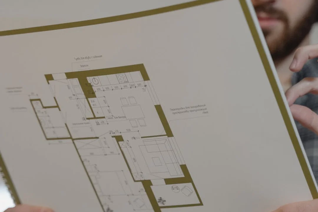 Close-up of a person holding and examining a large architectural floor plan