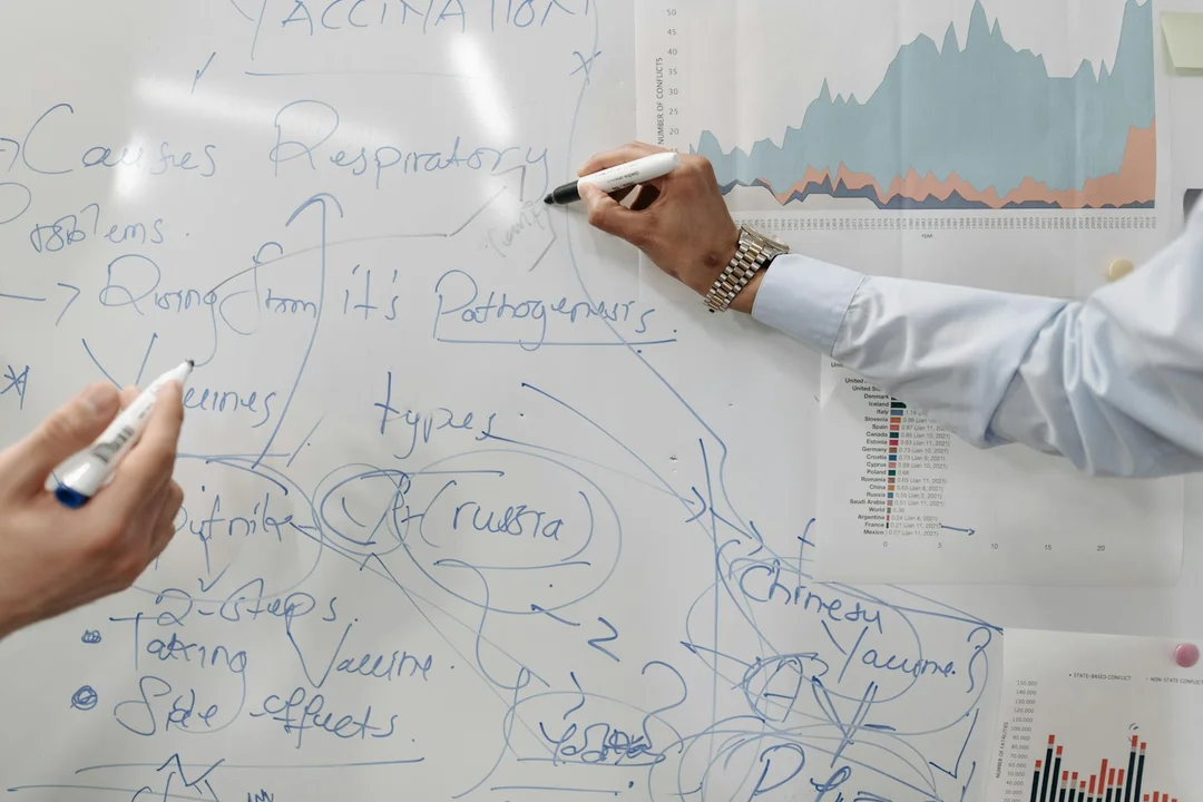 Two professionals annotate a whiteboard filled with diagrams and notes, representing governance planning for a homeowners association board.