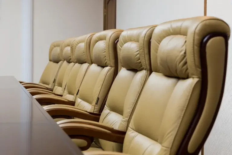Row of beige leather conference chairs lined up along a long table in a boardroom.