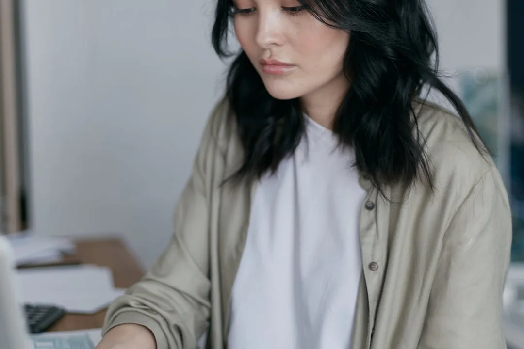 Person seated at a desk reviewing financial documents, illustrating the process of evaluating an HOA's budget and reserve fund health.