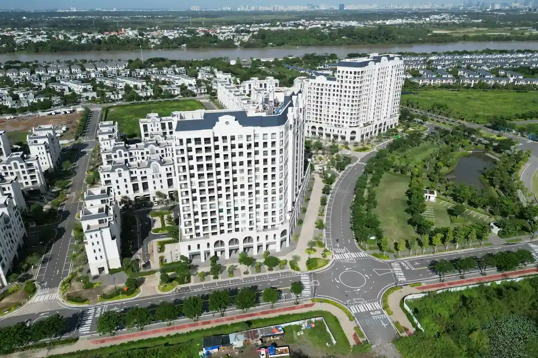 Aerial view of a large HOA community with white multi-story buildings, tree-lined streets, and landscaped green spaces.