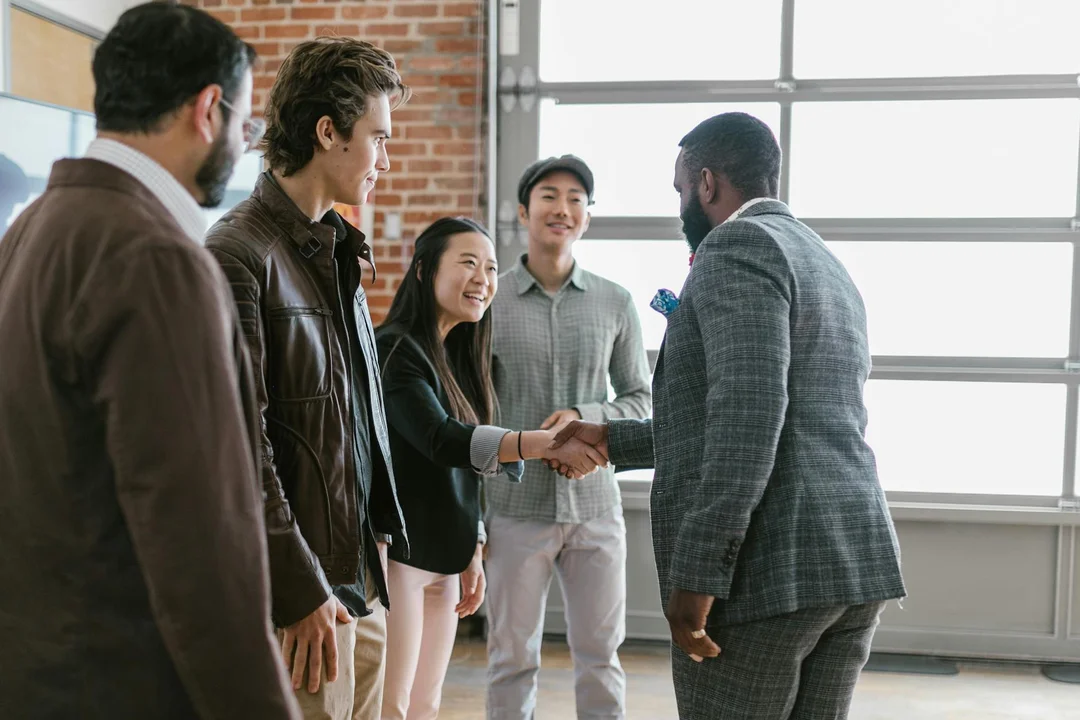 Diverse group of homeowners in a bright, modern room shake hands in a calm, constructive discussion