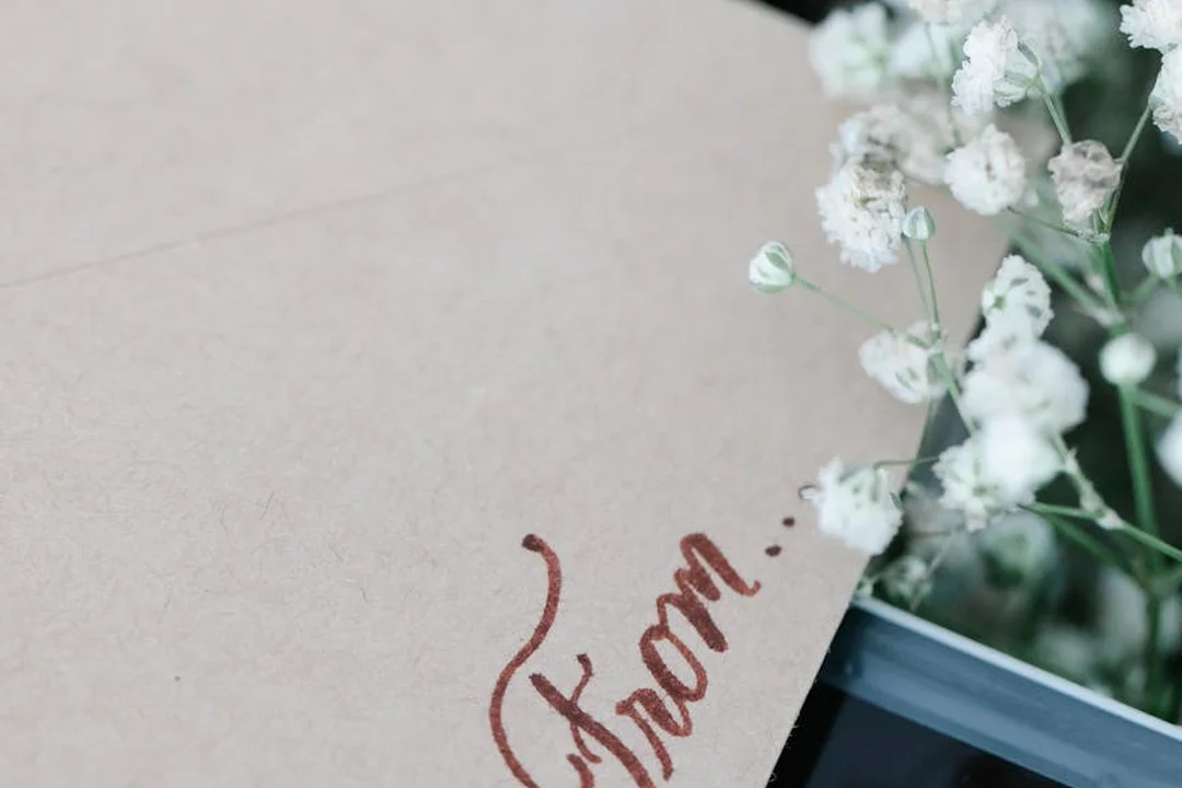 Brown envelope with handwritten text beside white flowers, symbolizing collecting documents and evidence for an HOA violation letter.
