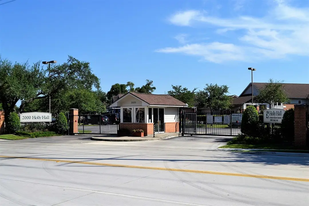 Gated HOA entrance with a guard booth and brick entry walls
