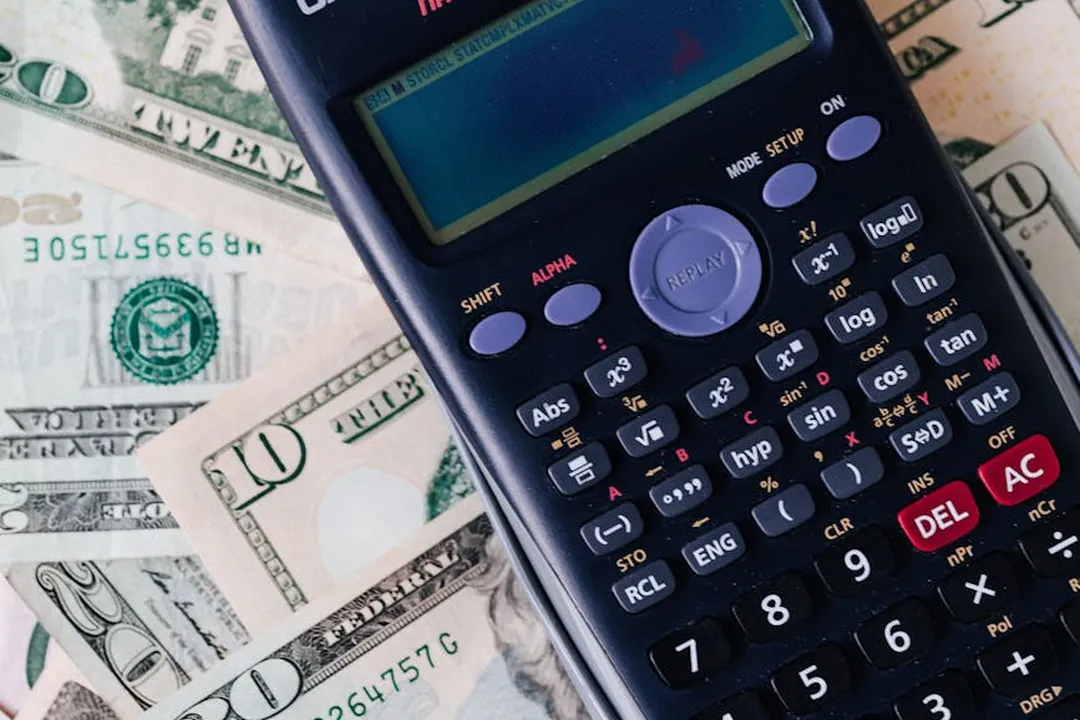 Calculator on top of scattered U.S. dollar bills, symbolizing financial management of HOA fines.