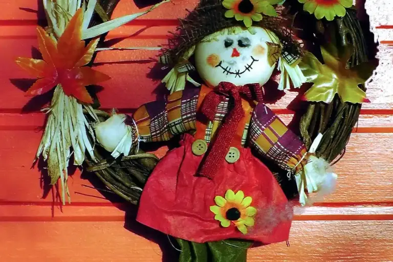 Decorative autumn wreath featuring a smiling snowman figure in a red dress, set against an orange wooden background.