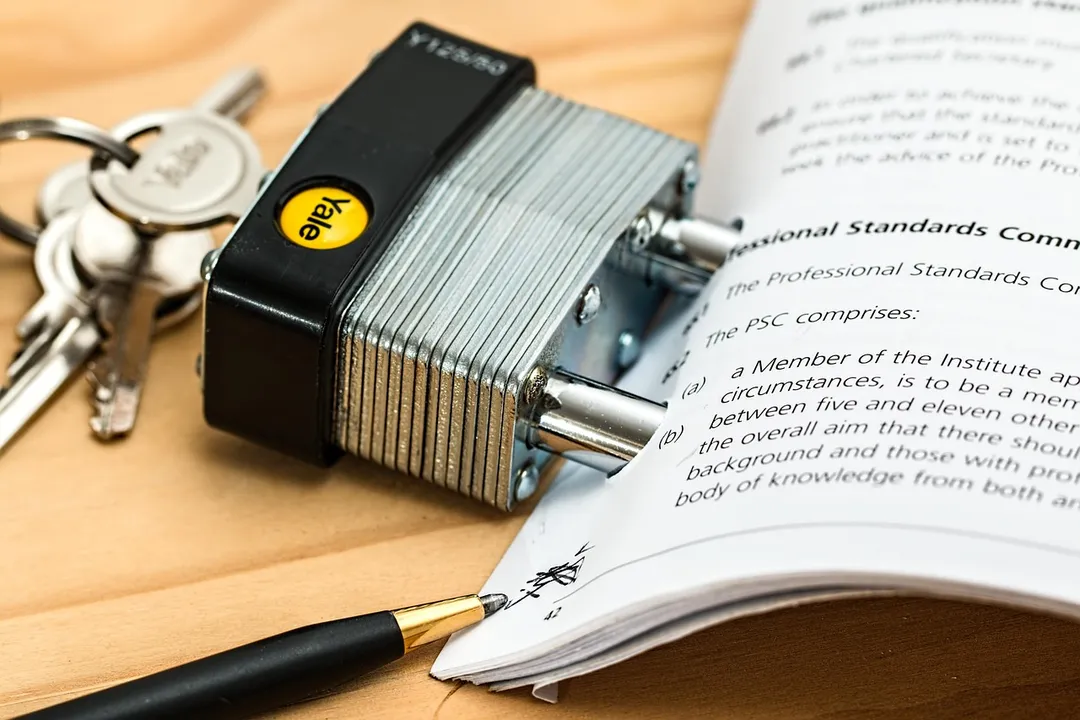 Padlock and keys beside an open document about HOA governing standards on a wooden desk