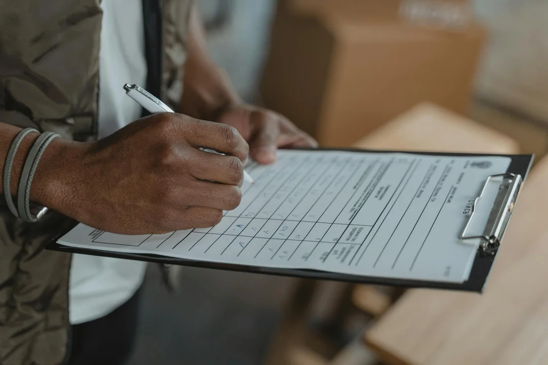 A person holding a clipboard and writing on a checklist form, representing preparation for an HOA health check.