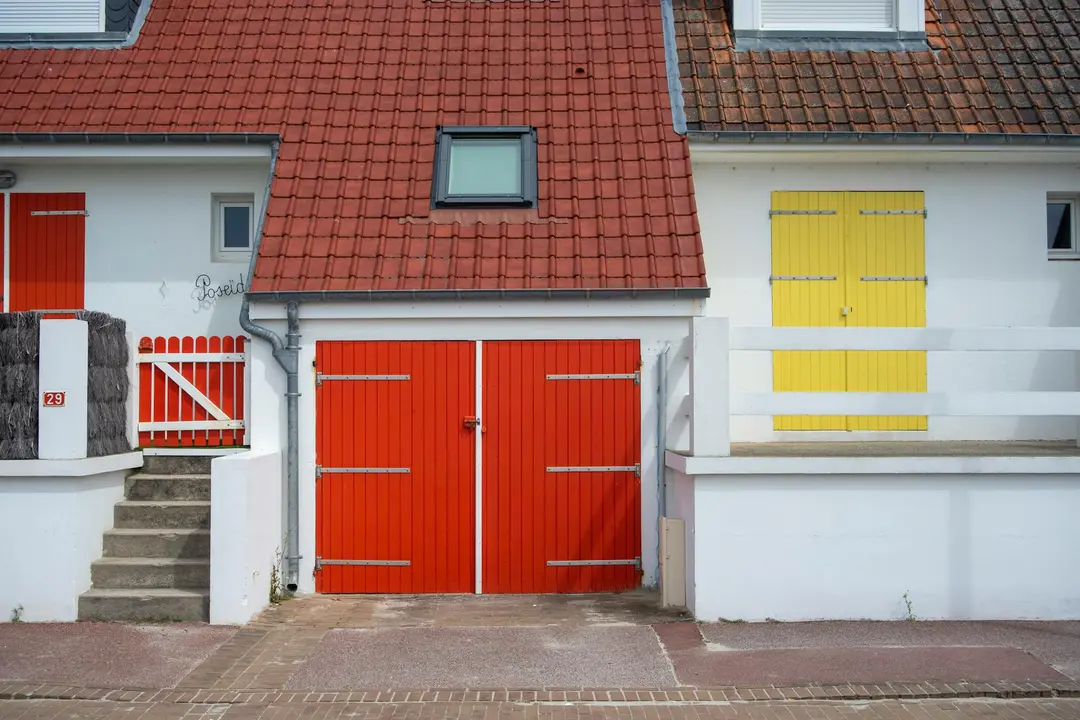 Row of townhouses in an HOA community with bold red doors and a yellow shutter, illustrating uniform design standards.