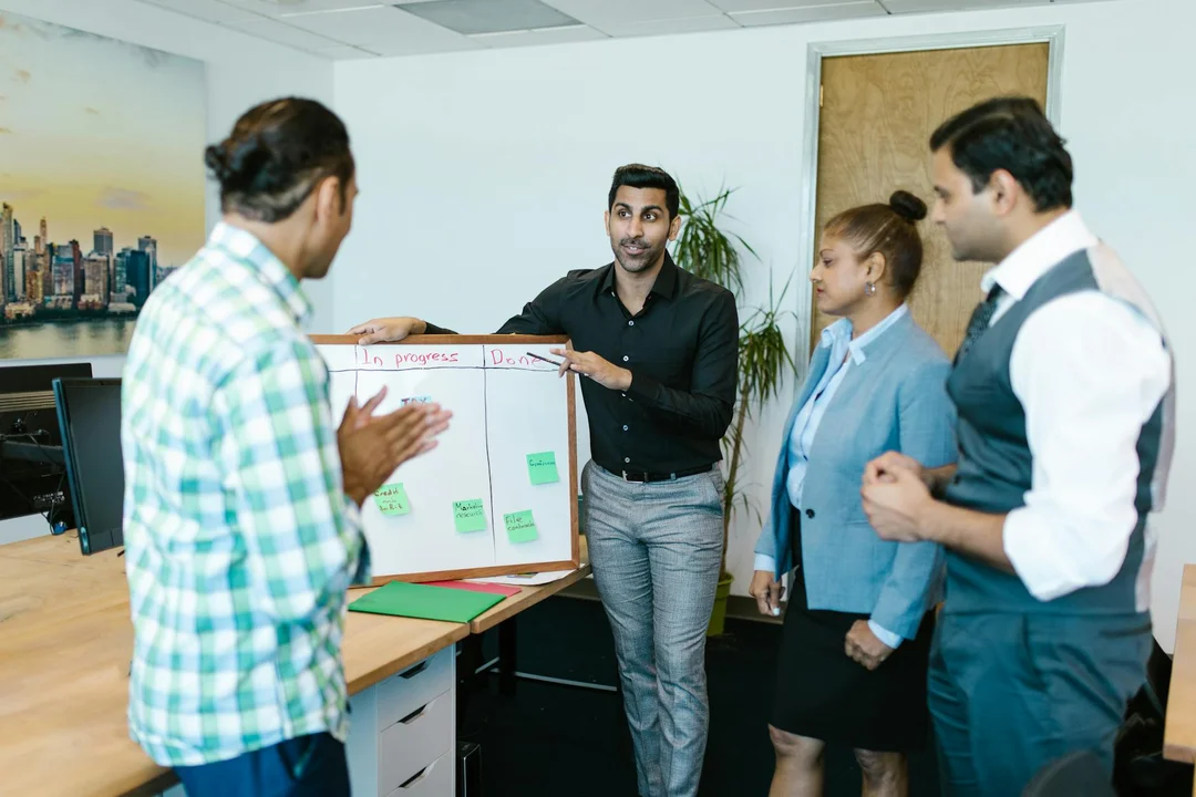 A diverse group of HOA board members in an office discussing insurance and risk management strategies around a whiteboard with sticky notes.