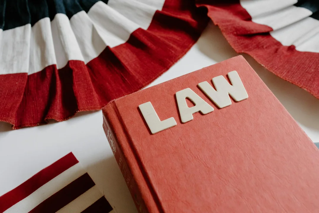 Red law book with the word LAW on the cover, surrounded by red, white, and black decorative ribbons.