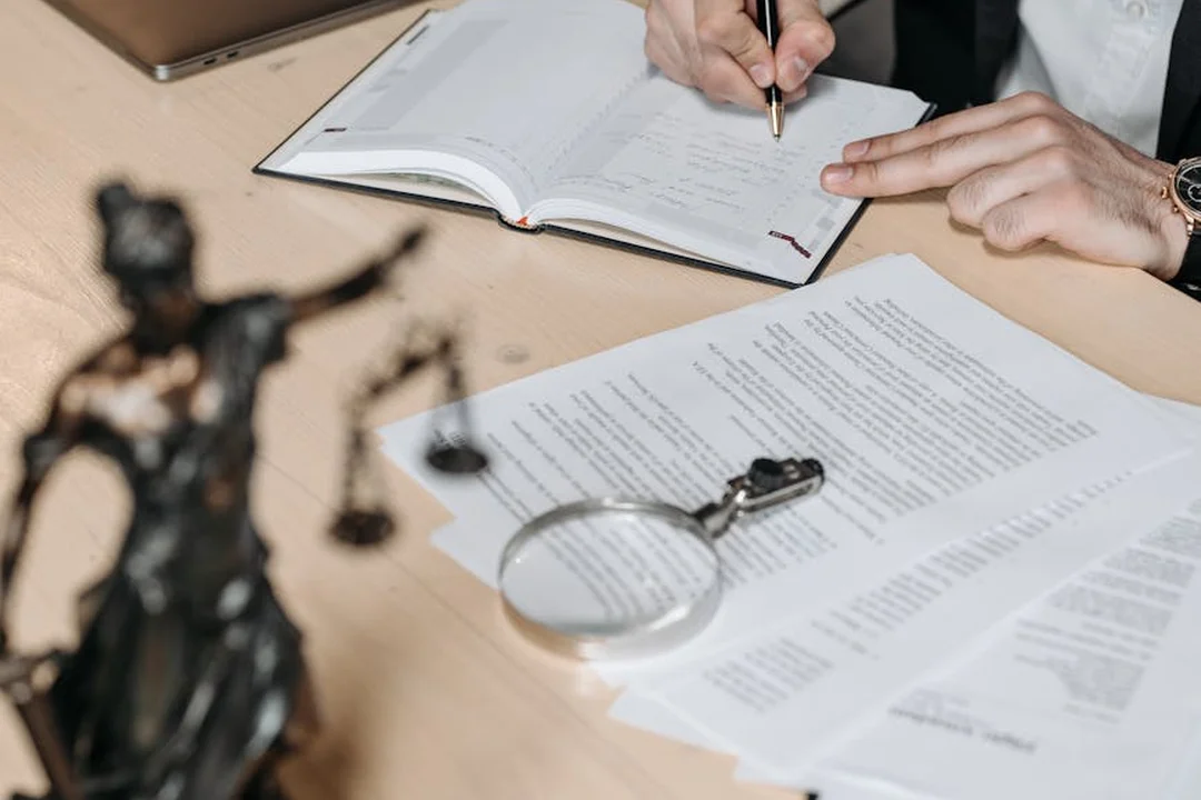 Close-up of hands taking notes over documents with a magnifying glass on a desk, symbolizing evaluation and contract review