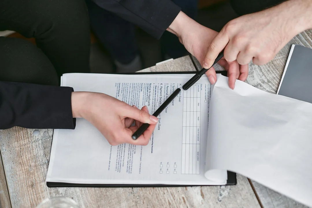 Two people sign a document on a clipboard during a mediation or meeting.