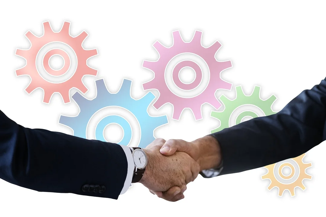 Two professionals shake hands with colorful gears in the background, symbolizing mediation and collaboration in HOA disputes.