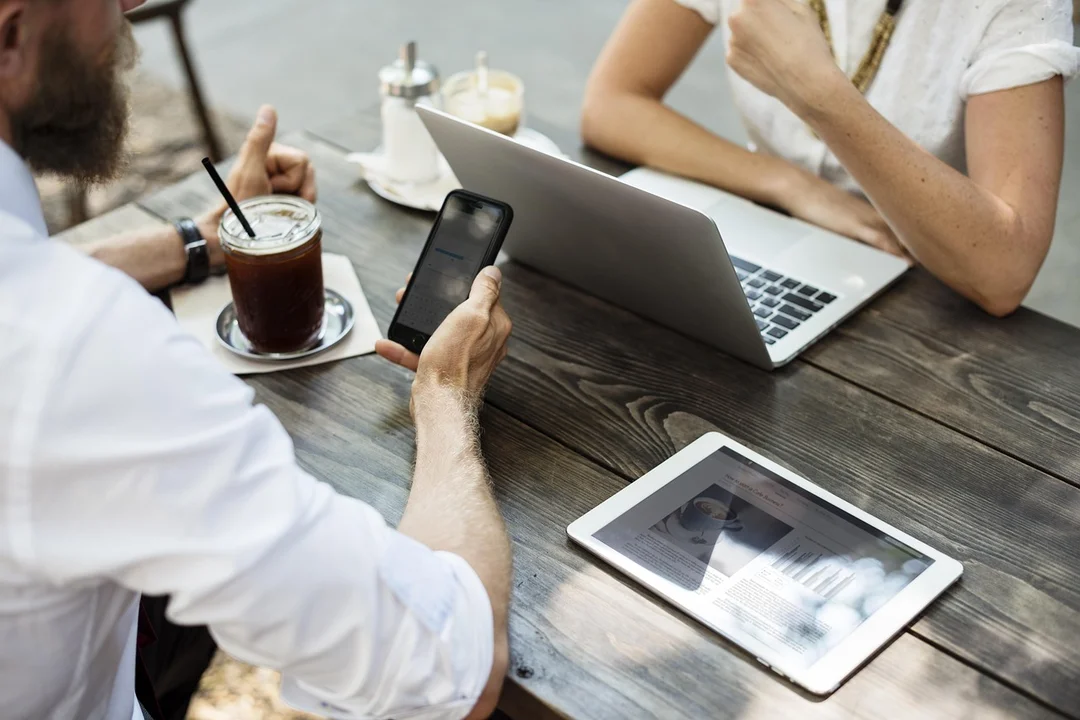 People at a table with a laptop, smartphone, and tablet discussing HOA governance.