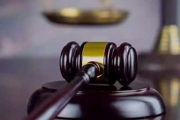 A judge's gavel resting on a wooden sound block with a softly blurred background, symbolizing governance and orderly HOA meetings.