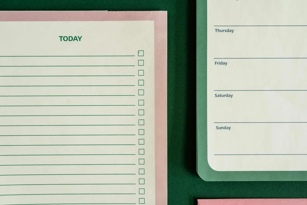 Close-up of pastel pink and green planners with checkboxes and weekly sections, symbolizing organization and preparation for HOA meetings.