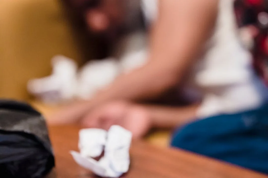 Close-up of a meeting table with crumpled papers and a blurred person in the background, suggesting decision-making.