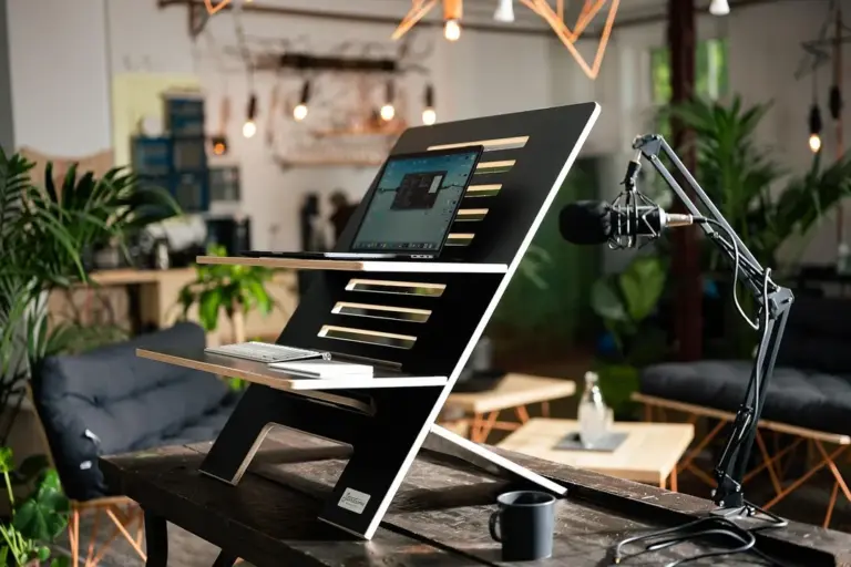 A microphone on a stand next to a tilted touchscreen monitor in a modern, plant-filled recording studio.
