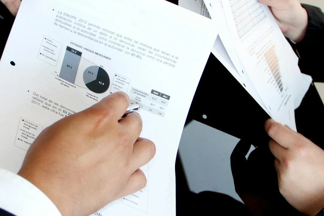 Hands of two people holding and examining printed meeting documents with charts