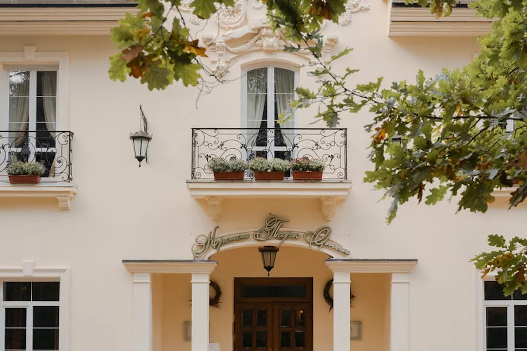 Residential building facade with an ornate front door, small balconies, and greenery, suggesting common areas within an HOA community.