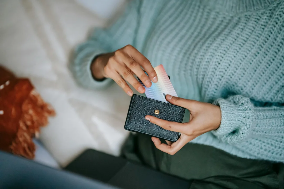Person holding a wallet and a credit card, ready to pay HOA fees online