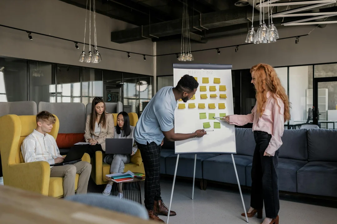 A diverse group of professionals in a modern office collaborate around a flip chart with sticky notes, planning proactive steps to prevent future HOA disputes.