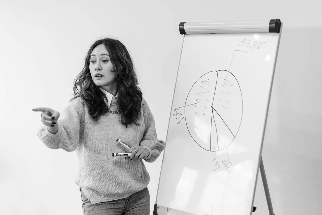 A woman points toward a pie chart on a flip chart during a presentation about proactive strategies to prevent HOA disputes.