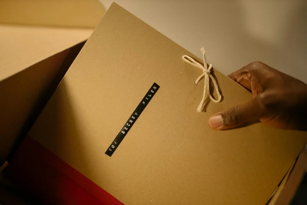 Close-up of a hand holding a brown envelope-style package tied with string, ready for review.