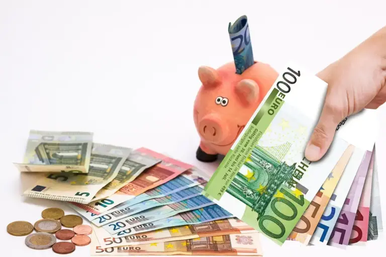 Piggy bank with a hand placing a 100-euro banknote among euro banknotes and coins, representing saving for a long-term HOA reserve fund.