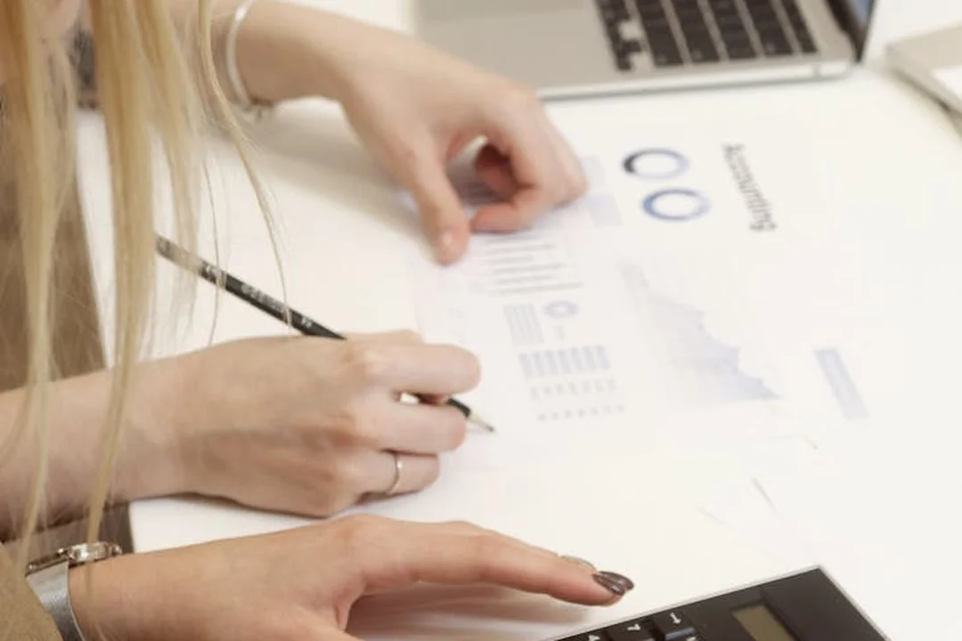 Close-up of hands writing on documents with charts and a calculator, illustrating financial planning for reserve funds.