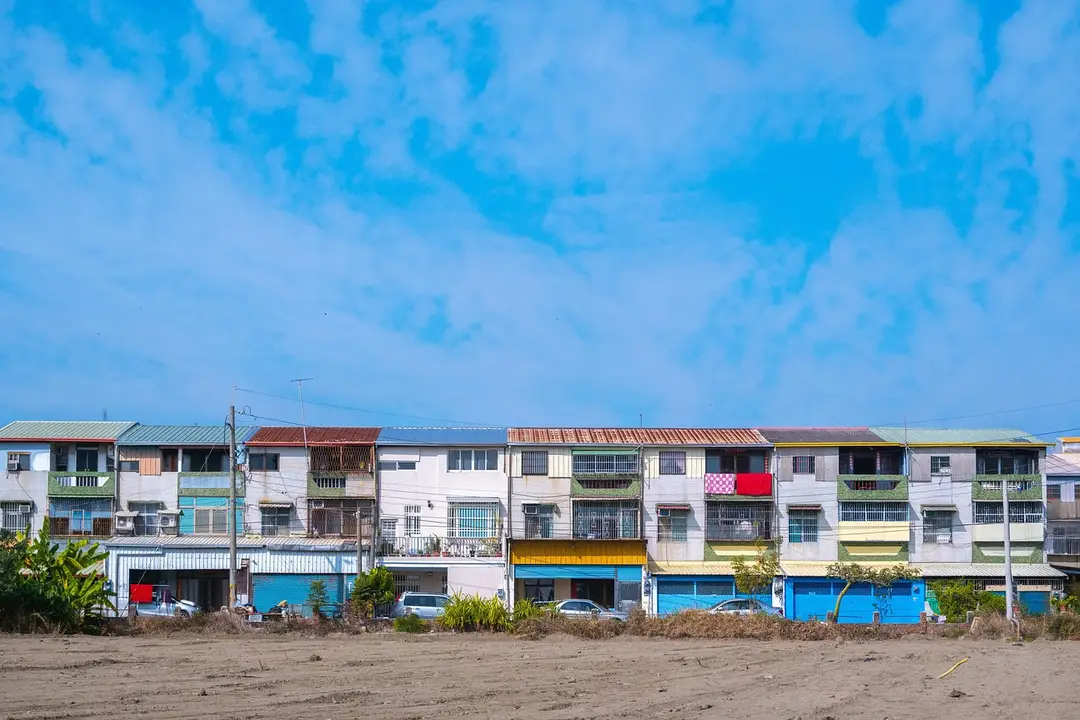 Row of colorful beachfront townhouses with balconies under a clear blue sky.