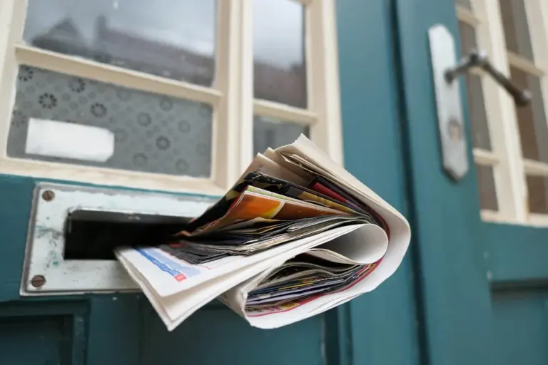 A bundle of letters protruding from a front-door mailbox slot.