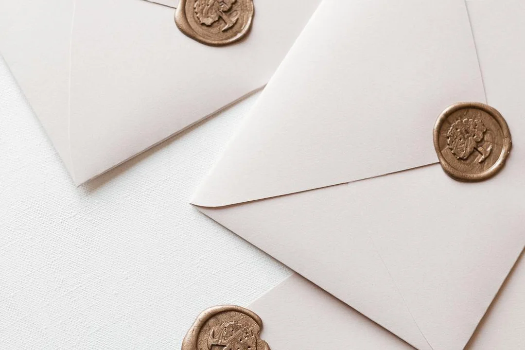 Close-up of white envelopes with wax seals scattered on a light surface