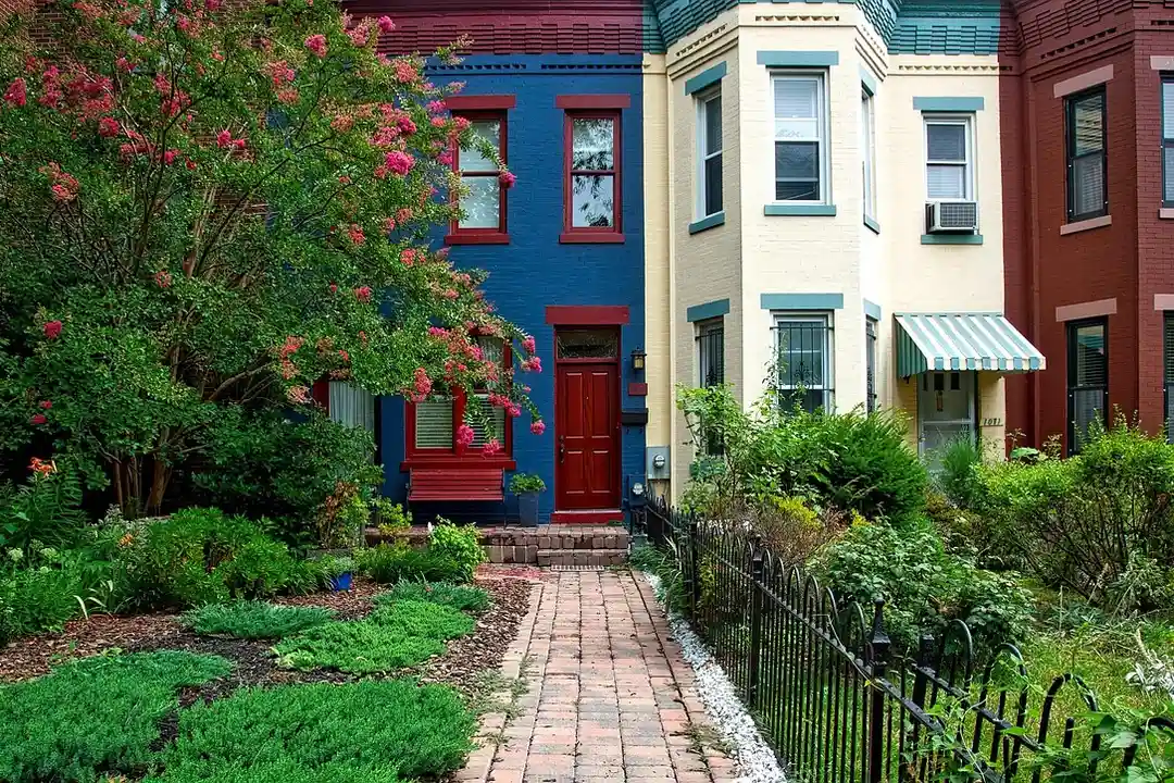 Colorful row houses with small front yards and a brick pathway in a residential HOA neighborhood