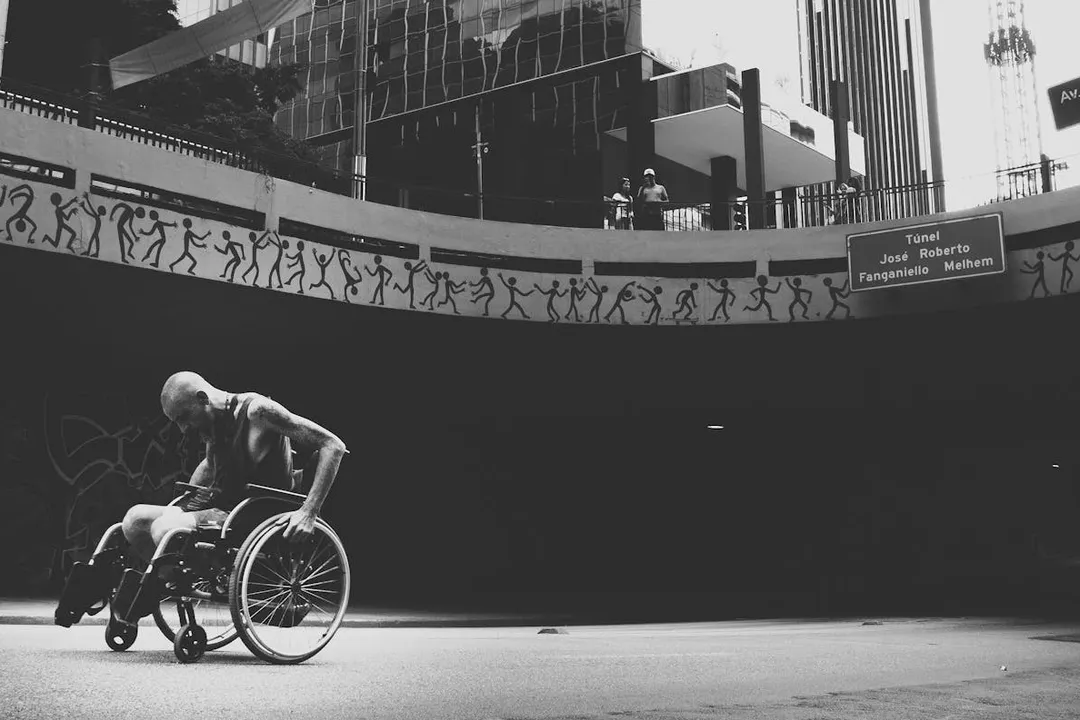 Black-and-white photo of a person in a wheelchair in an urban plaza, illustrating accessibility considerations for housing.