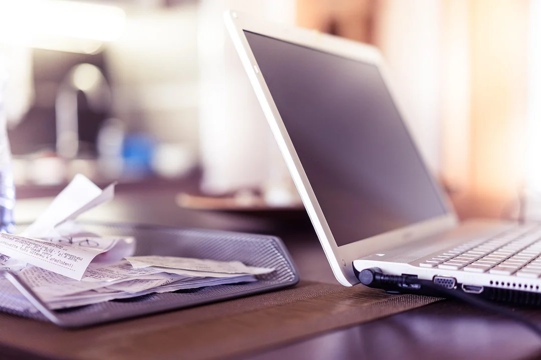 Laptop on a desk with scattered receipts, suggesting budgeting and expense tracking for HOA board activities.