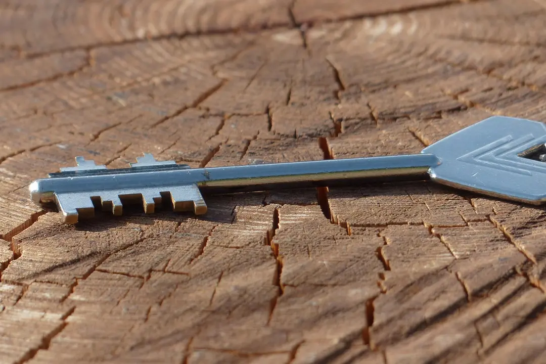 A metal key lies on a weathered wooden surface, illustrating the start of transitioning control.
