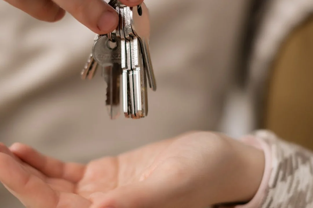 Close-up of hands exchanging keys, symbolizing lease agreements and HOA fee responsibilities