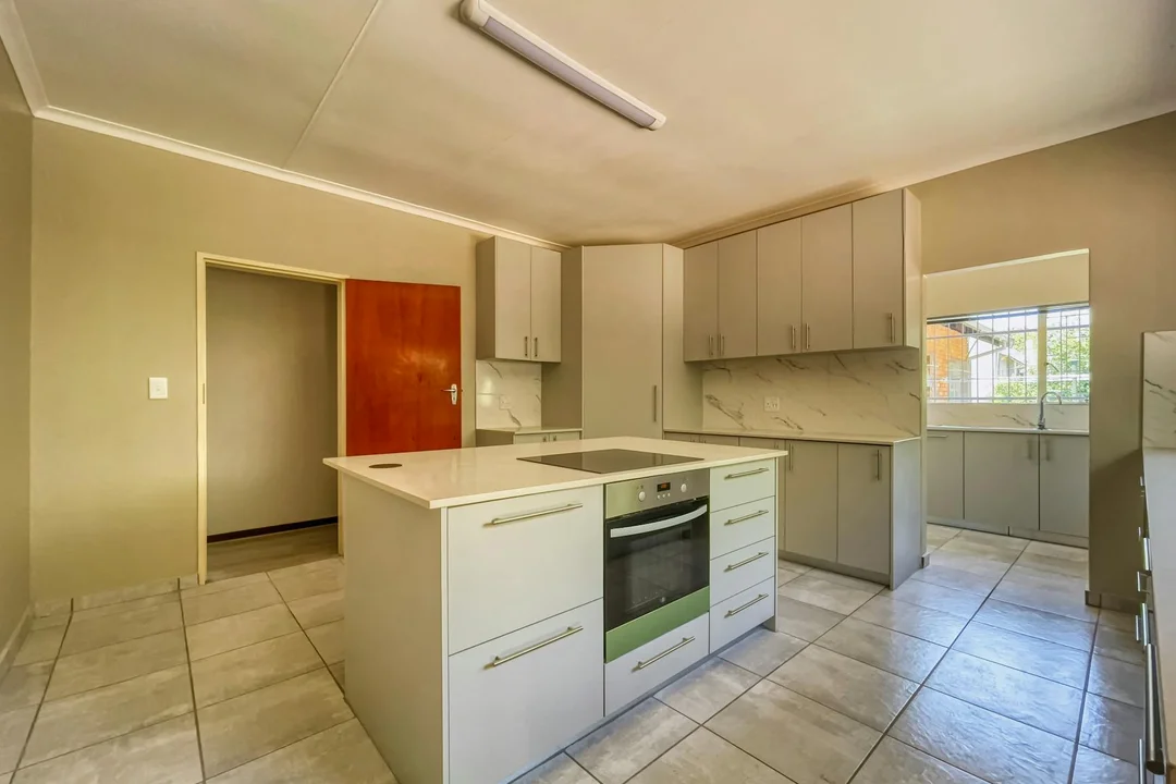 Bright, modern kitchen with gray cabinetry, central island, built-in oven, and tiled floor in an HOA-friendly interior renovation.