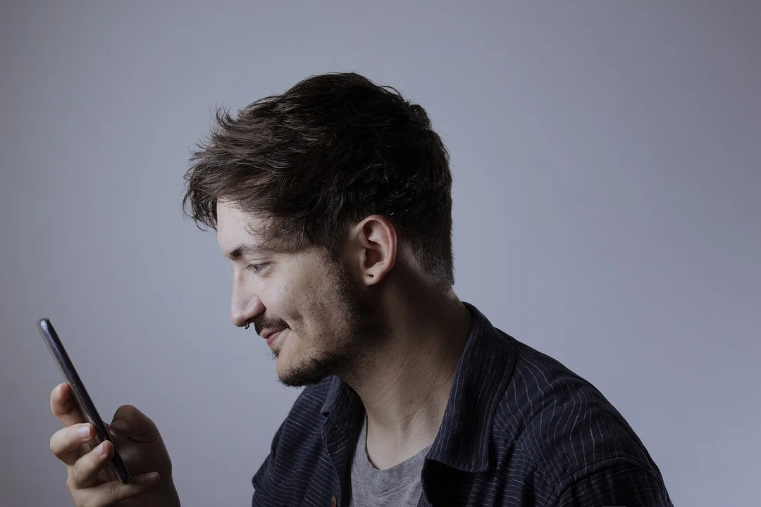 Profile view of a man looking at his smartphone, symbolizing user training and support after a tech upgrade.
