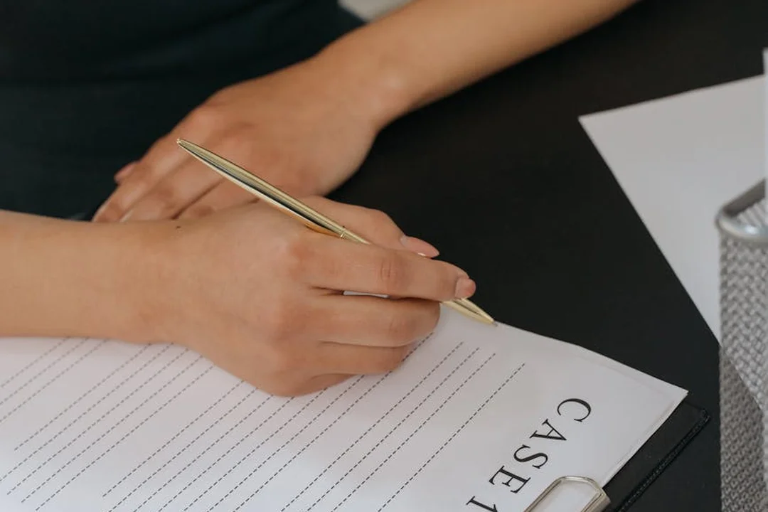 Close-up of hands writing with a pen on a lined document labeled CASE on a desk, illustrating evidence preparation for mediation.
