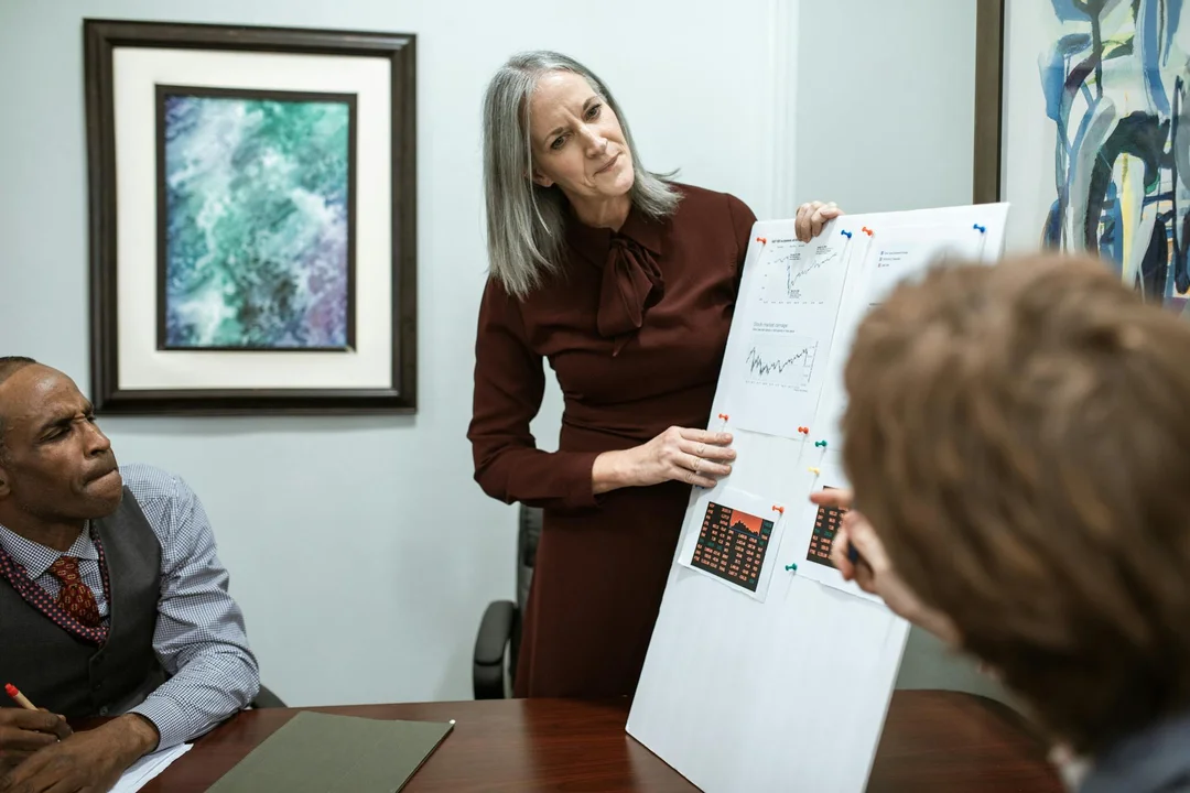 A mediator presents charts to clients during a mediation session in a conference room.