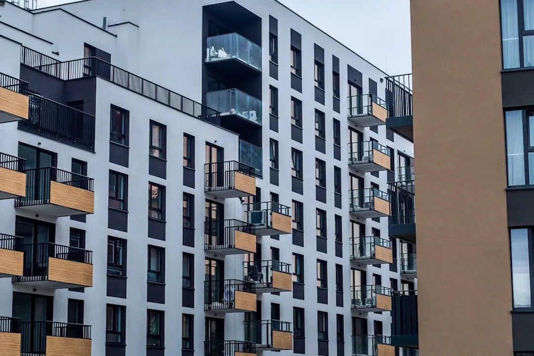Facade of a modern multi-story condo building with glass balconies and wooden railings