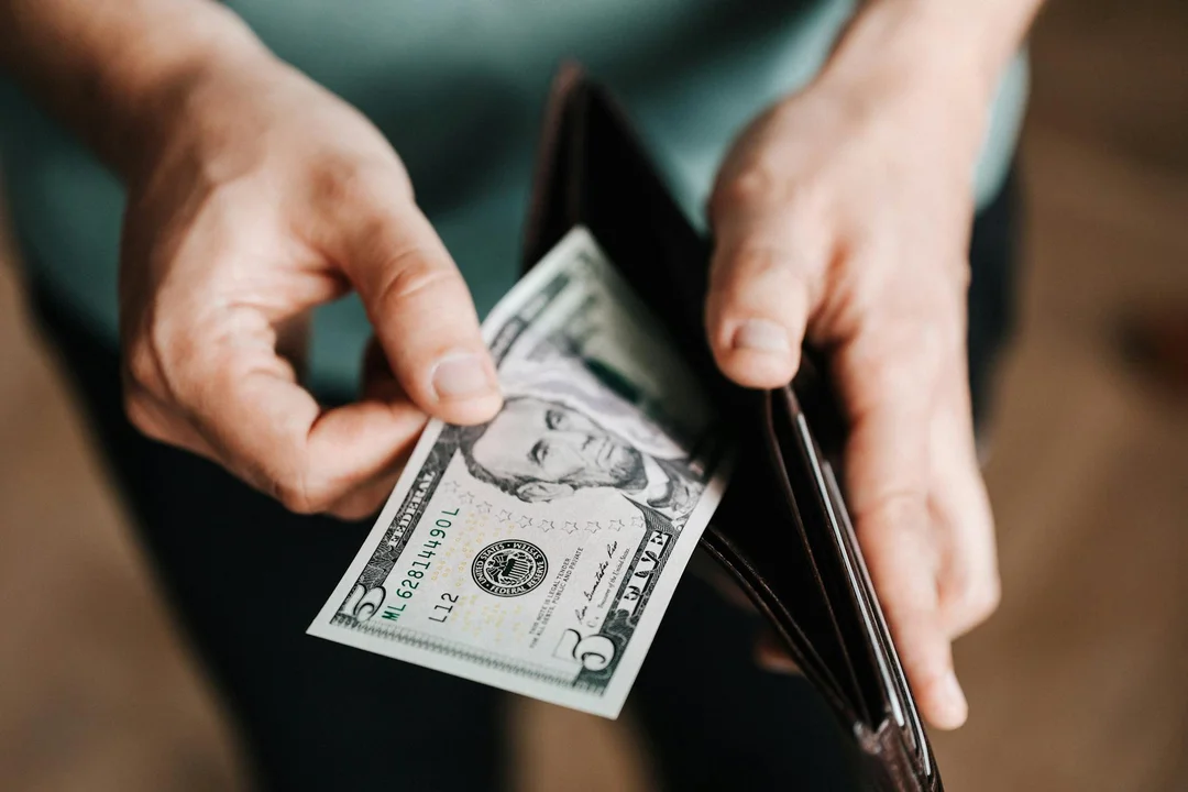 Close-up of hands holding a wallet with dollar bills