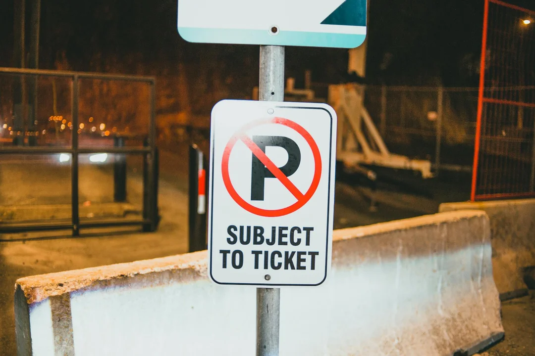Night scene with a 'Subject to Ticket' no-parking sign near a construction zone