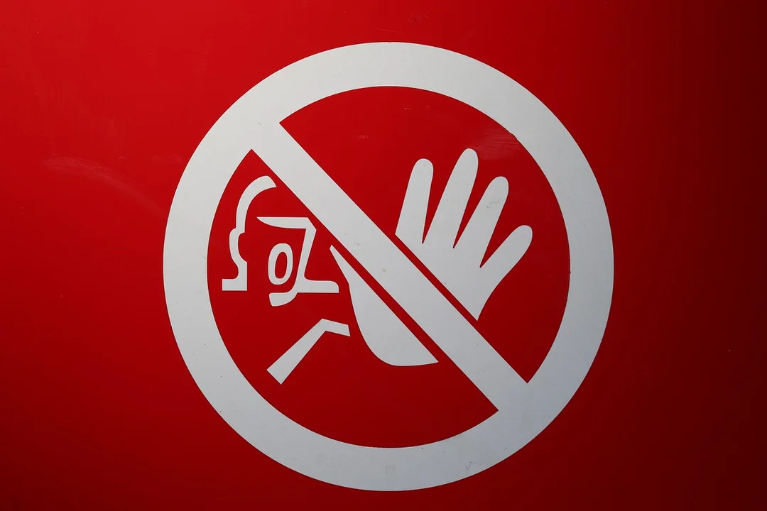 Red background with a white prohibition sign featuring a raised hand and a small figure, symbolizing stopping discriminatory enforcement by an HOA