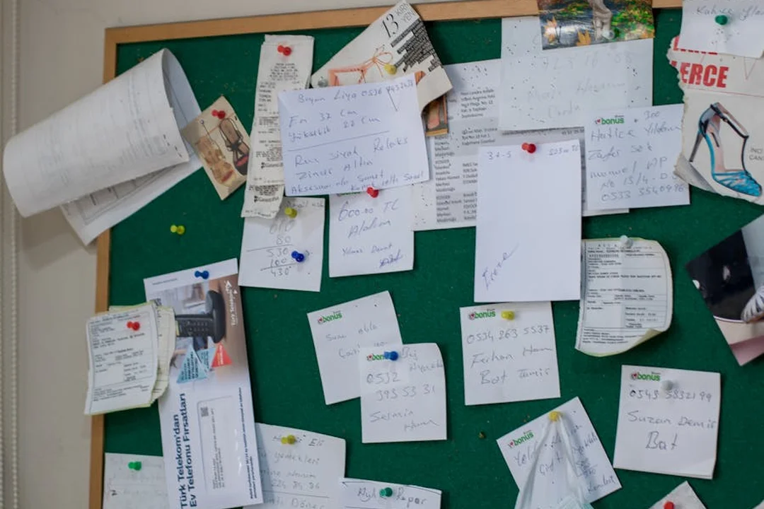 Bulletin board filled with handwritten notes pinned on a green corkboard